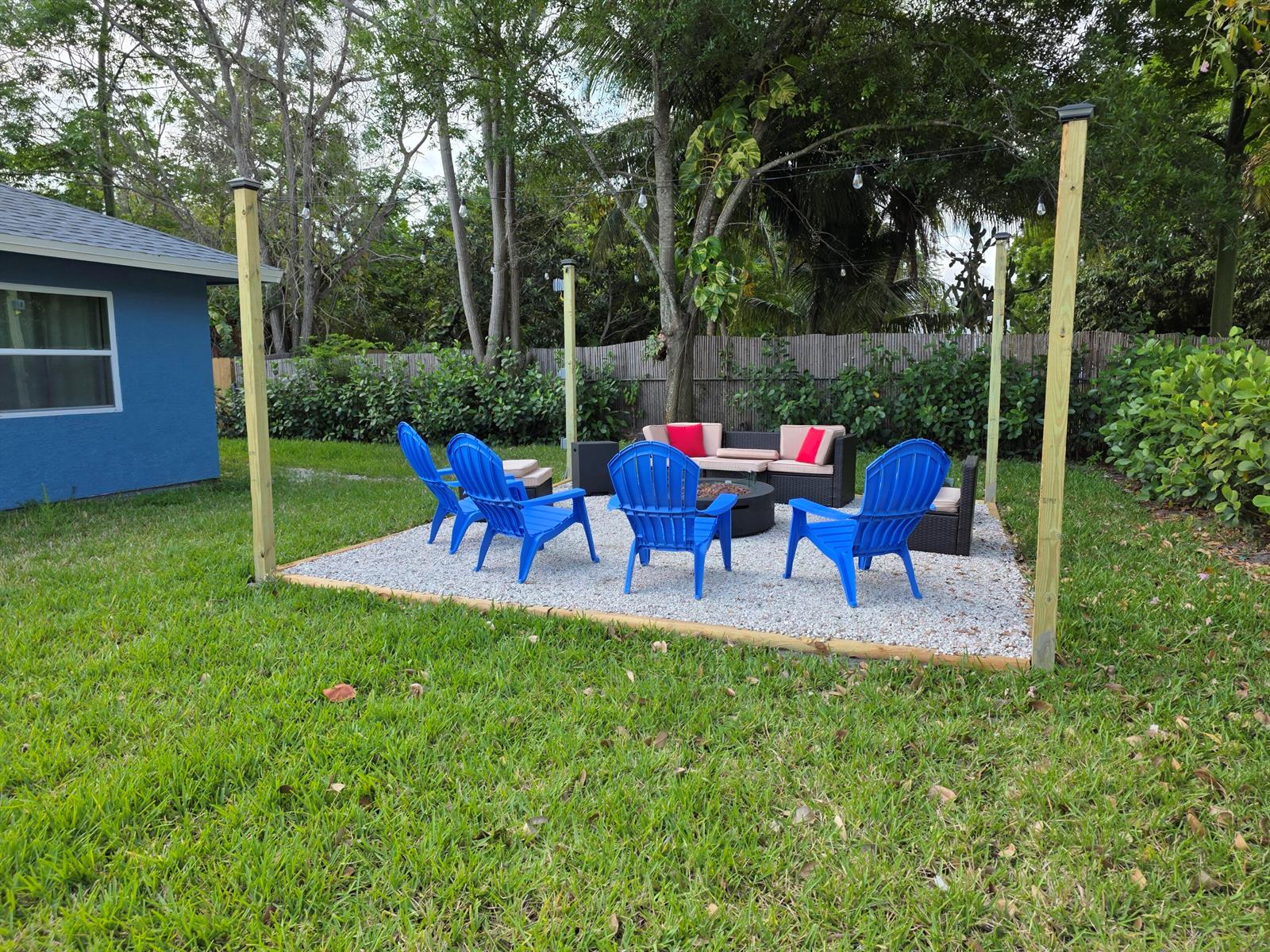 A backyard patio area features a gravel floor, four blue Adirondack chairs, and a sofa — 106 E Chandler Road, Cloud Lake FL 33406, CLOUD LAKE, FL