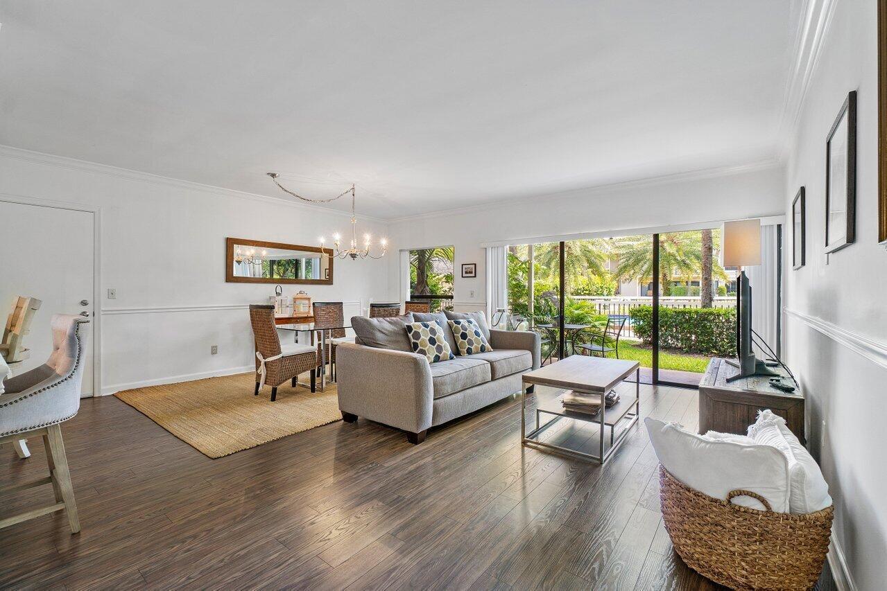 A living and dining room with wood floors, a gray sofa, and sliding glass doors — 11863 Wimbledon Circle # 433, Wellington FL 33414, WELLINGTON, FL