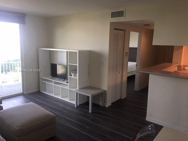A living room with dark wood-look flooring, a white media console, and an adjacent kitchen — 816 NW 11th St # 1104, Miami FL 33136, MIAMI, FL
