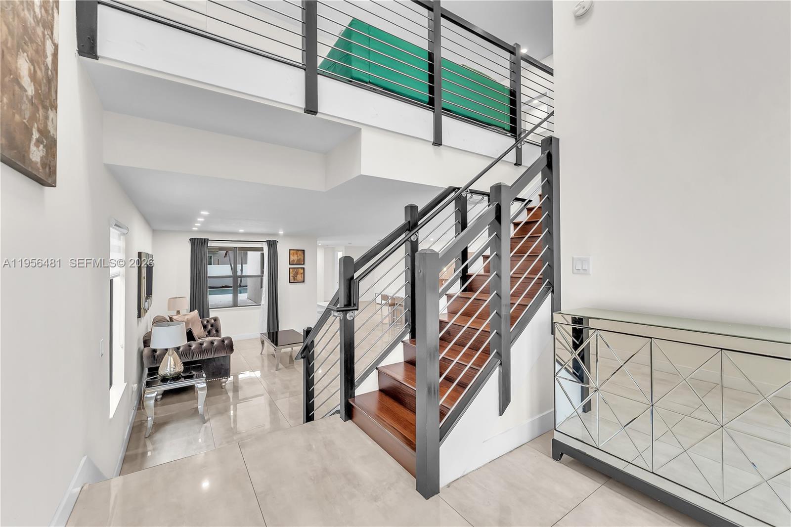A modern staircase with dark wood treads and metal railings leads to a lofted area — 10250 NW 76th Ter, Doral FL 33178, DORAL, FL