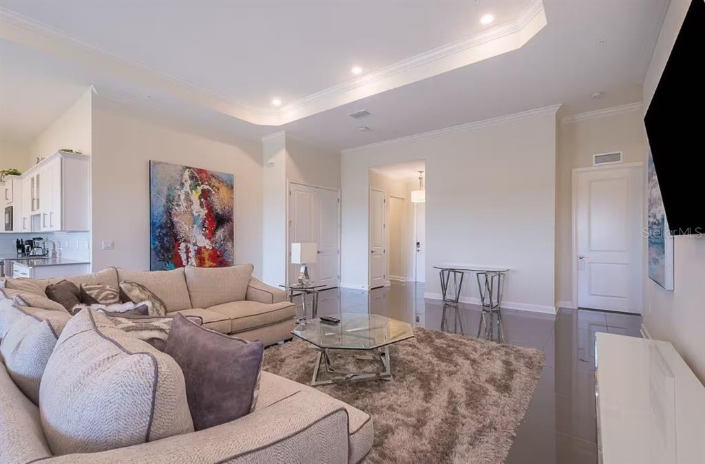 A living room features a beige sectional sofa, a glass coffee table, and tile flooring — 4731 CLOCK TOWER DRIVE UNIT 401, KISSIMMEE, FL