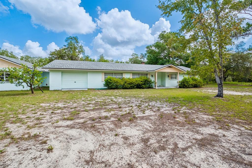 A single-story house with a light green exterior, a garage, and a sandy front yard — 6267 CLANCE ROAD, KEYSTONE HEIGHTS, FL