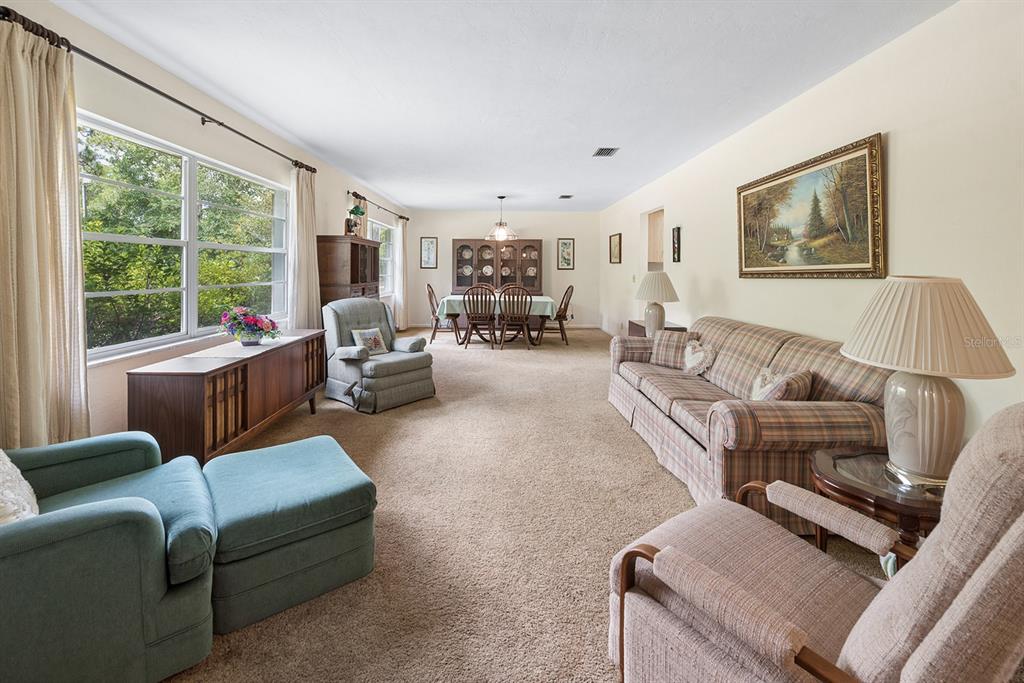 A spacious living and dining area with beige carpeting, neutral walls, and traditional furniture — 6267 CLANCE ROAD, KEYSTONE HEIGHTS, FL