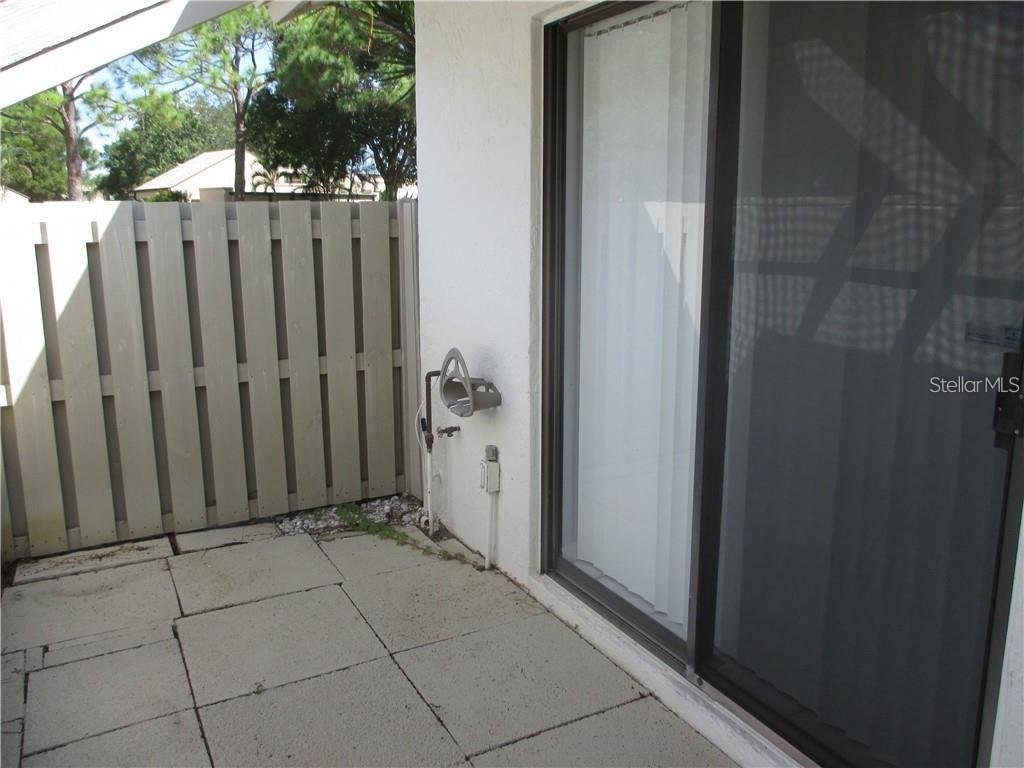 A concrete patio features a privacy fence, a sliding glass door, and an exterior water spigot — 5358 MYRTLE UNIT 52, SARASOTA, FL