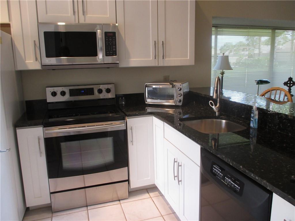 A kitchen features white cabinets, stainless steel appliances, and black granite countertops — 5358 MYRTLE UNIT 52, SARASOTA, FL