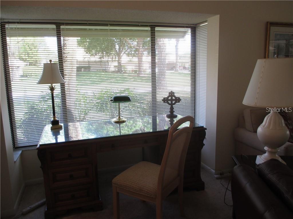 A home office features a glass-topped wooden desk, a chair, and large windows with blinds — 5358 MYRTLE UNIT 52, SARASOTA, FL