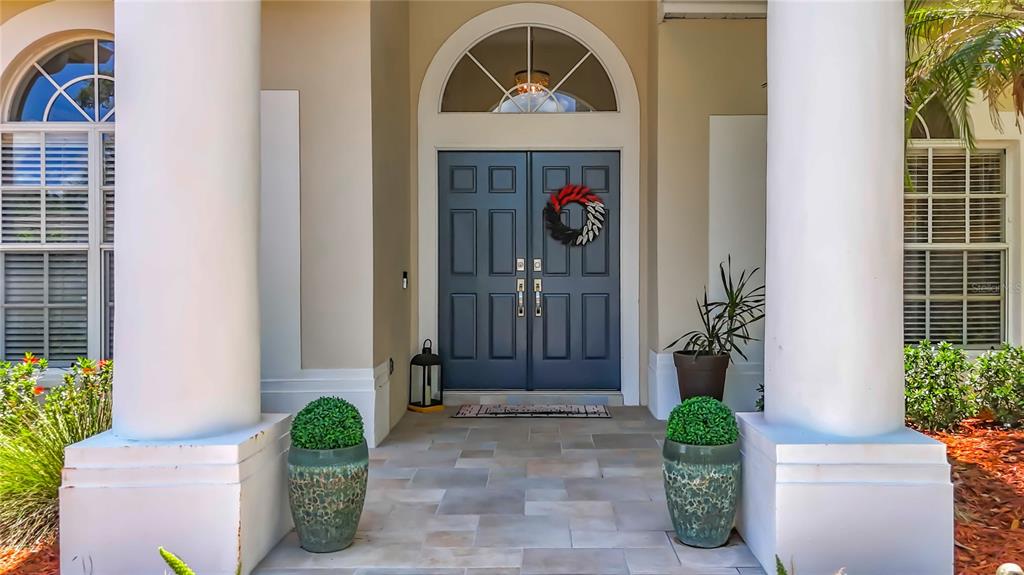 A front entrance features double blue doors, white columns, and potted plants on a patio — 1266 BERKSHIRE LANE, TARPON SPRINGS, FL