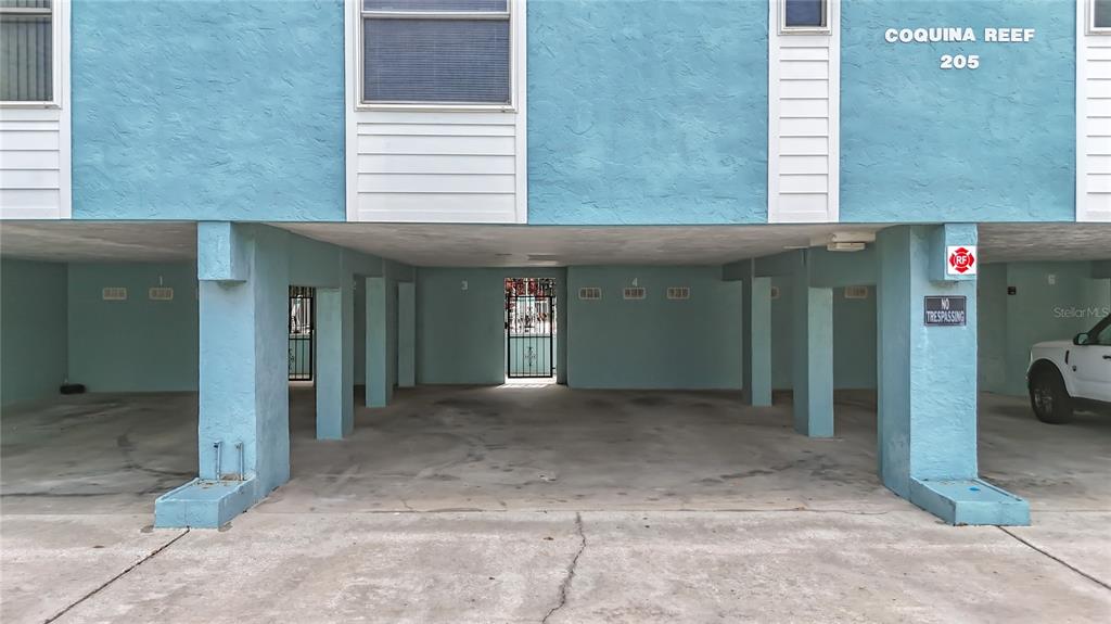 The ground level of a blue building features a covered parking area with numbered spaces — 205 HIGHLAND AVENUE UNIT 3, BRADENTON BEACH, FL