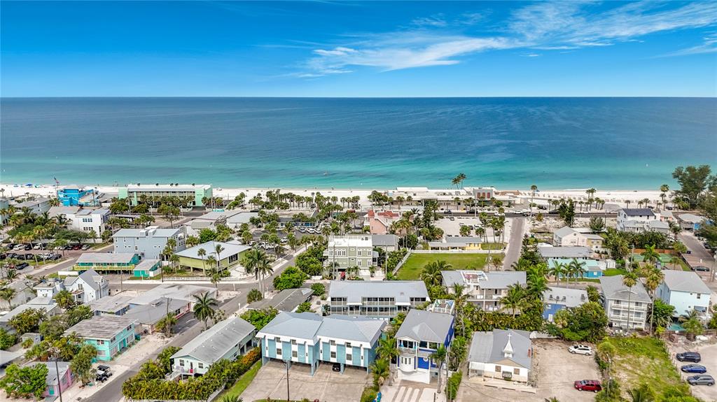 An aerial view shows a coastal neighborhood with houses, palm trees, and a sandy beach — 205 HIGHLAND AVENUE UNIT 3, BRADENTON BEACH, FL