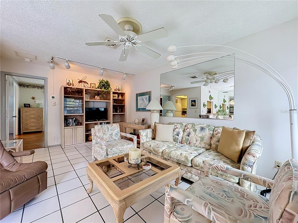A living room features tile floors, a floral sofa, patterned armchairs, and a large wall mirror — 205 HIGHLAND AVENUE UNIT 3, BRADENTON BEACH, FL