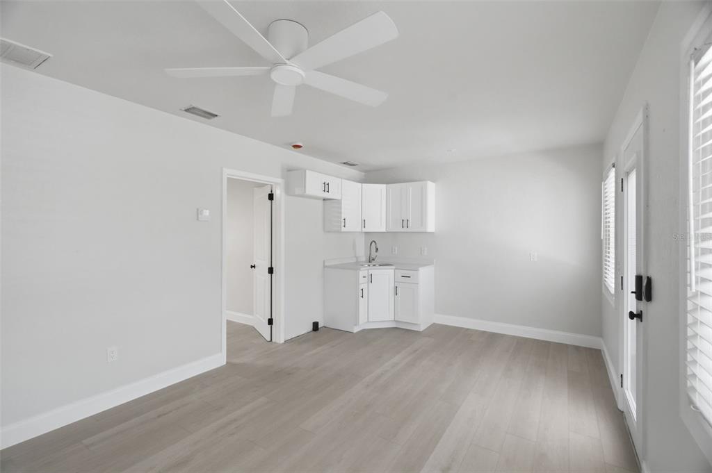 A room with light wood-look flooring, a white ceiling fan, and a small corner kitchenette — 3101 BEACH BOULEVARD S UNIT 1-5, GULFPORT, FL