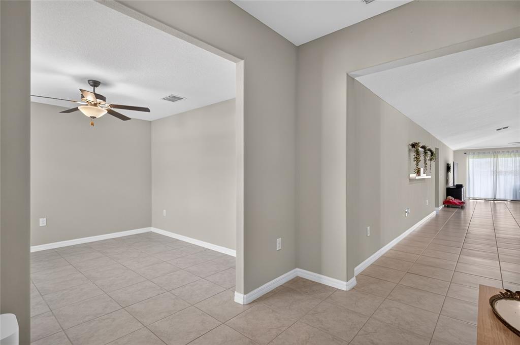 An interior view showing a tiled room with a ceiling fan and an adjacent hallway — 5420 LESLIE CANYON DRIVE, WIMAUMA, FL