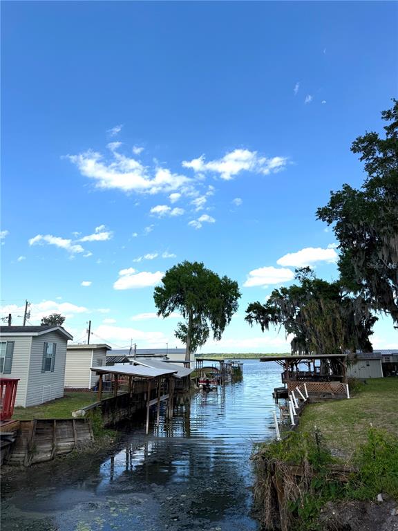 A canal leads from a residential shoreline toward a large lake under a blue sky — 748 CR 477A, LAKE PANASOFFKEE, FL