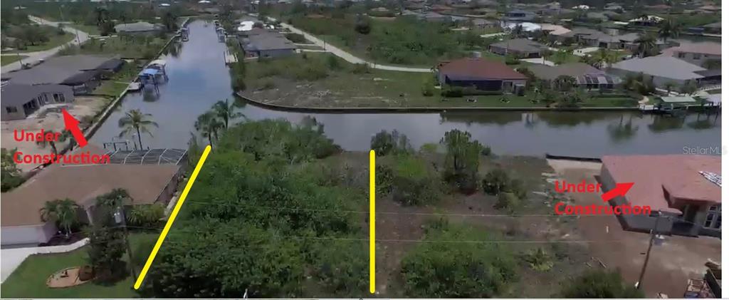 An aerial view shows a vacant waterfront lot situated between two houses under construction — 15028 ACORN CIRCLE, PORT CHARLOTTE, FL