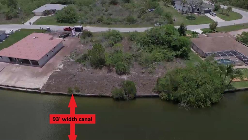 An aerial view shows a vacant waterfront lot situated between two houses along a canal — 15028 ACORN CIRCLE, PORT CHARLOTTE, FL