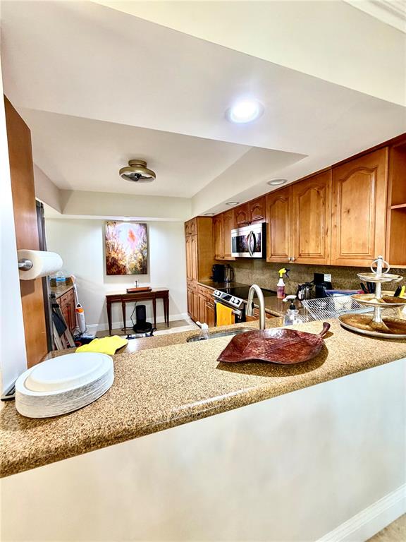 A kitchen features wood cabinets, granite countertops, and a breakfast bar overlooking a dining area — 6075 GLENDALE DRIVE, BOCA RATON, FL