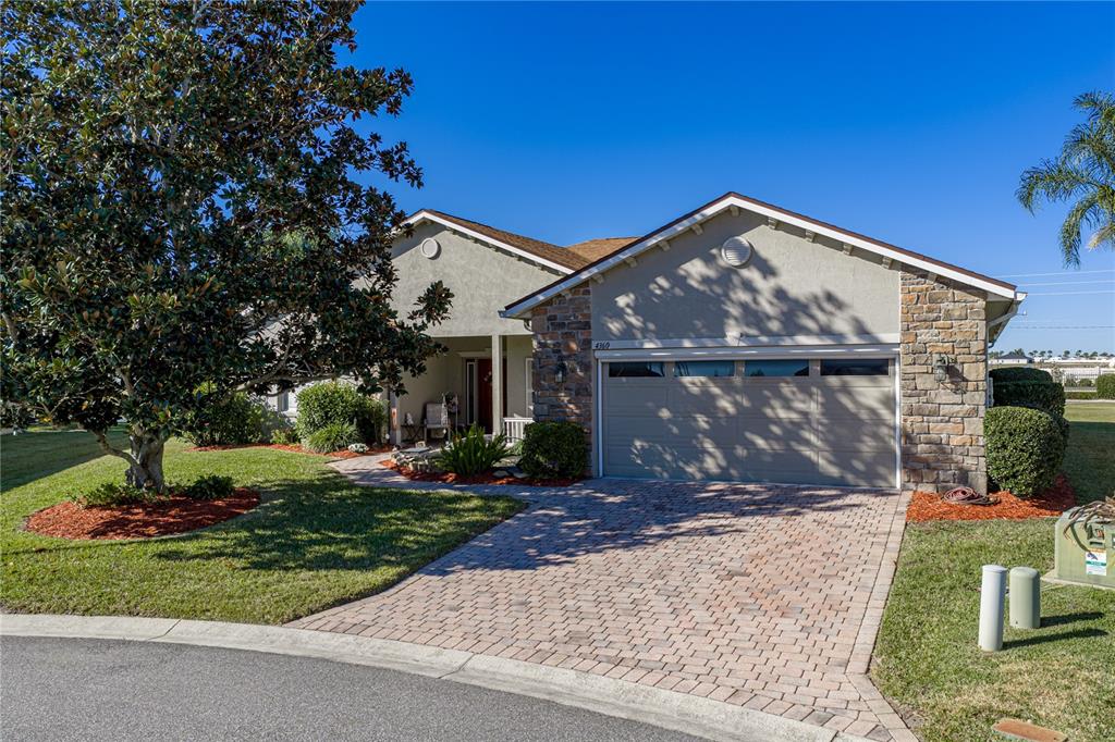 A single-story house with a stone-accented facade, a two-car garage, and a paved driveway — 4360 ASHTON CLUB DRIVE, LAKE WALES, FL