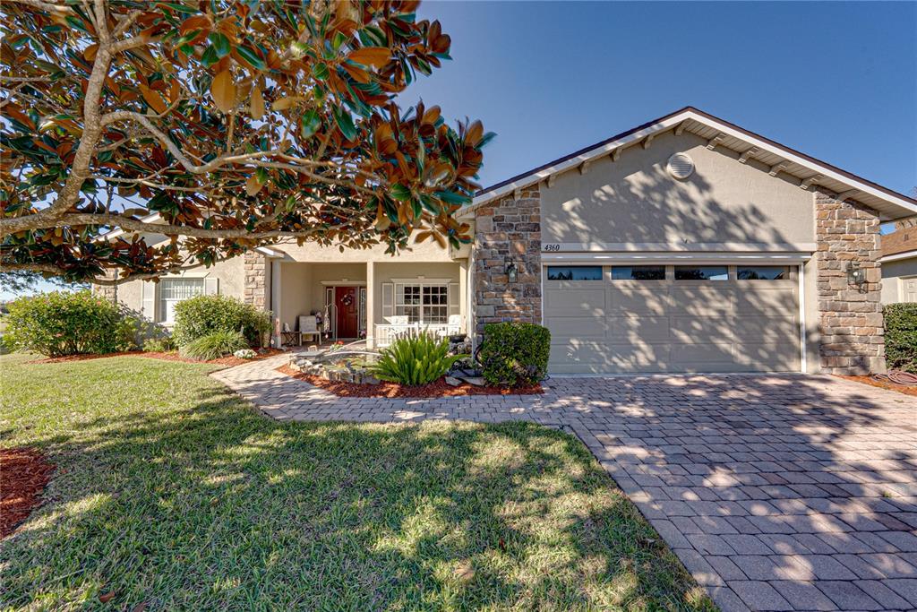A paved walkway leads to a covered front porch with a white railing and door — 4360 ASHTON CLUB DRIVE, LAKE WALES, FL