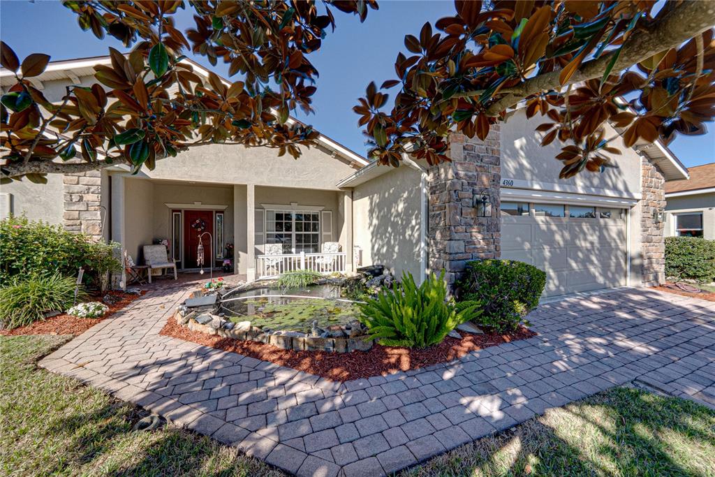 A paved walkway leads to a covered front porch with a white railing and entryway — 4360 ASHTON CLUB DRIVE, LAKE WALES, FL