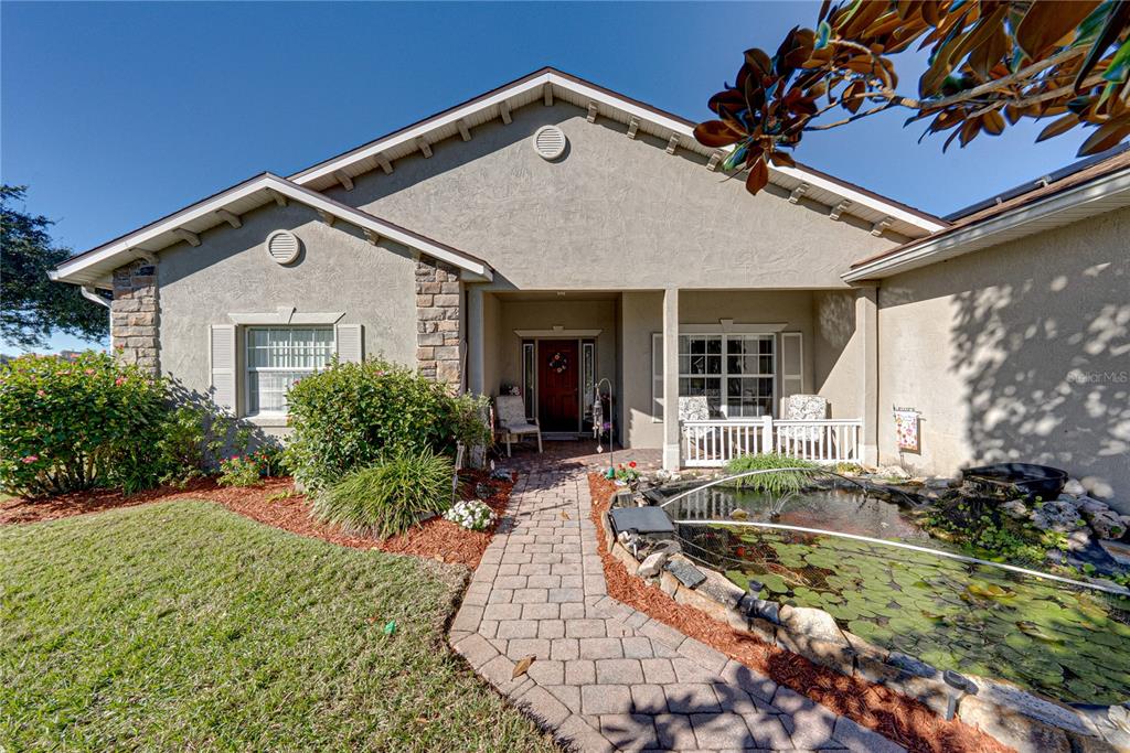 A front porch with a white railing sits beside a mulched garden bed and walkway — 4360 ASHTON CLUB DRIVE, LAKE WALES, FL