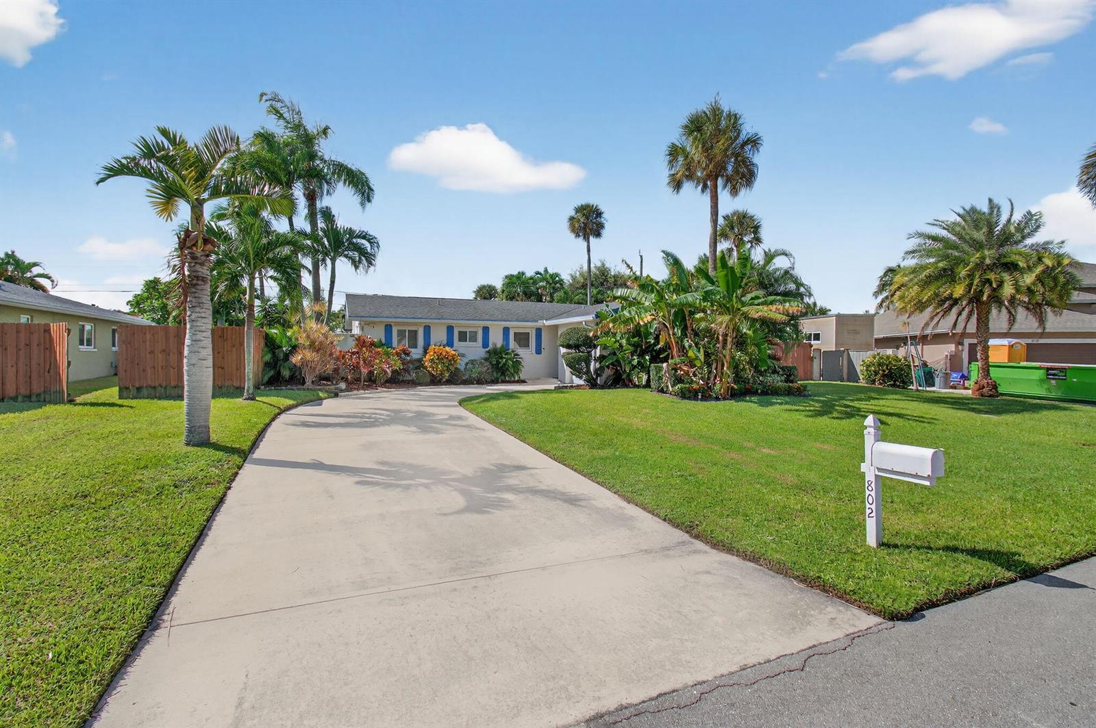 A single-story house with a concrete driveway, palm trees, and a white mailbox — 802 Mallard Drive, Delray Beach FL 33444, DELRAY BEACH, FL