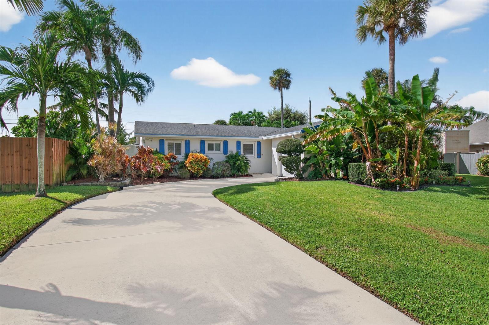 A single-story house with a curved driveway, blue shutters, and lush tropical landscaping — 802 Mallard Drive, Delray Beach FL 33444, DELRAY BEACH, FL