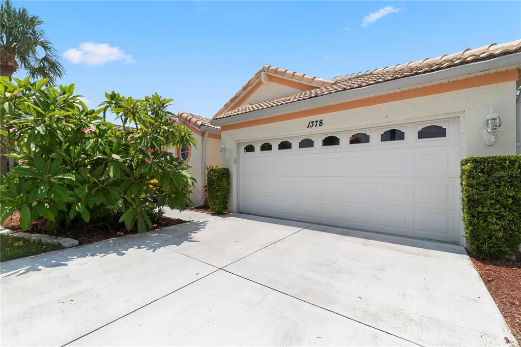 A white garage door with windows is attached to a house with a tiled roof — 1378 CAPRI ISLES BOULEVARD UNIT 61, VENICE, FL