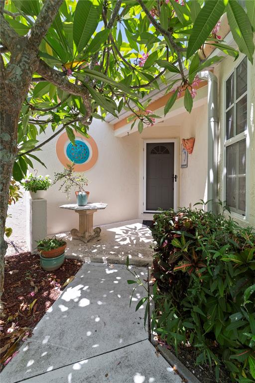 A concrete walkway leads to a front entrance with a dark door and potted plants — 1378 CAPRI ISLES BOULEVARD UNIT 61, VENICE, FL