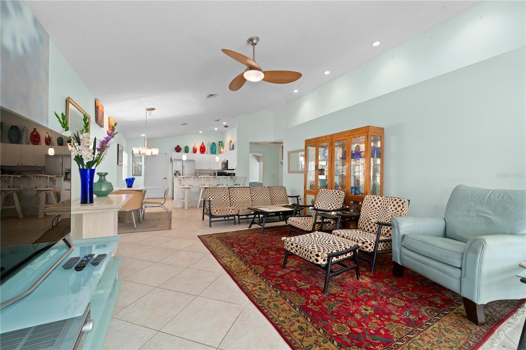 A living room with tile floors, a patterned rug, and a light blue armchair — 1378 CAPRI ISLES BOULEVARD UNIT 61, VENICE, FL