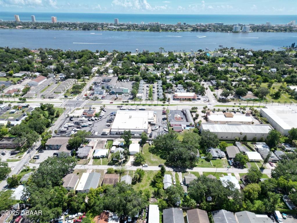 An aerial view shows a commercial area with buildings, parking lots, and a nearby waterway — 724 STATE AVENUE, DAYTONA BEACH, FL