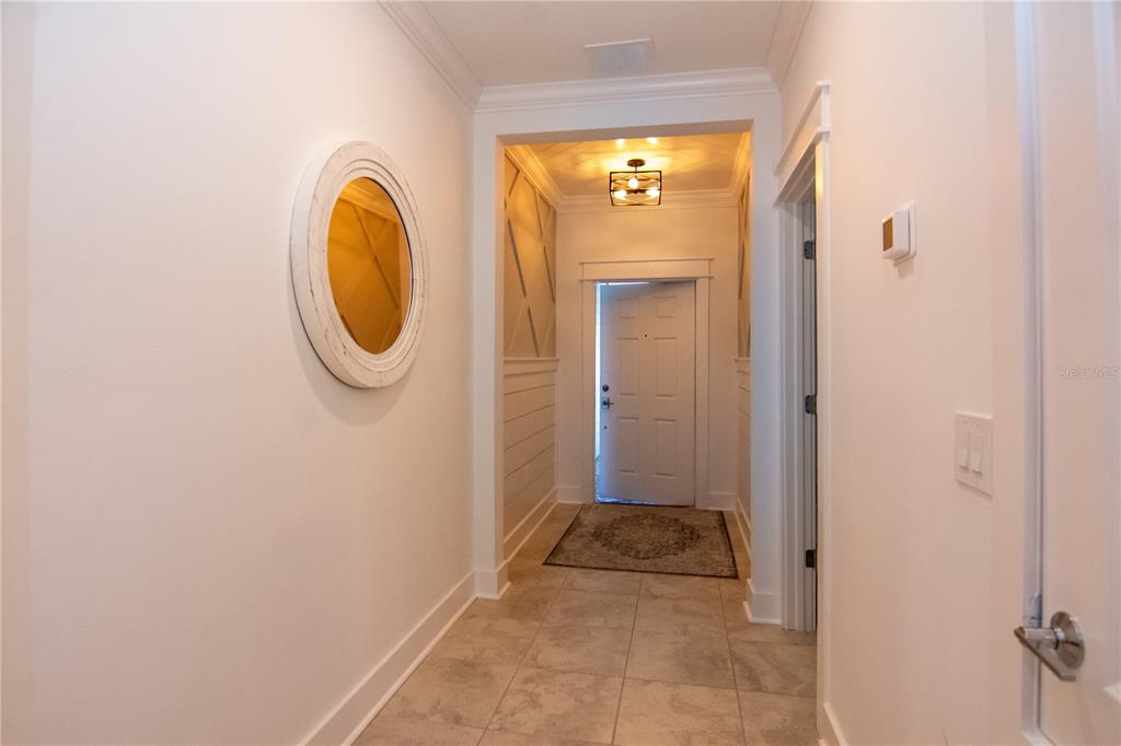 A bright entryway features tile flooring, white shiplap walls, a round mirror, and a front door — 2006 MYRTLE PINE STREET, KISSIMMEE, FL