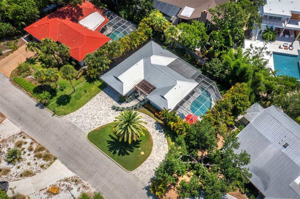 An aerial view shows a house with a metal roof, pool enclosure, and circular driveway — 622 TROPICAL CIRCLE, SARASOTA, FL