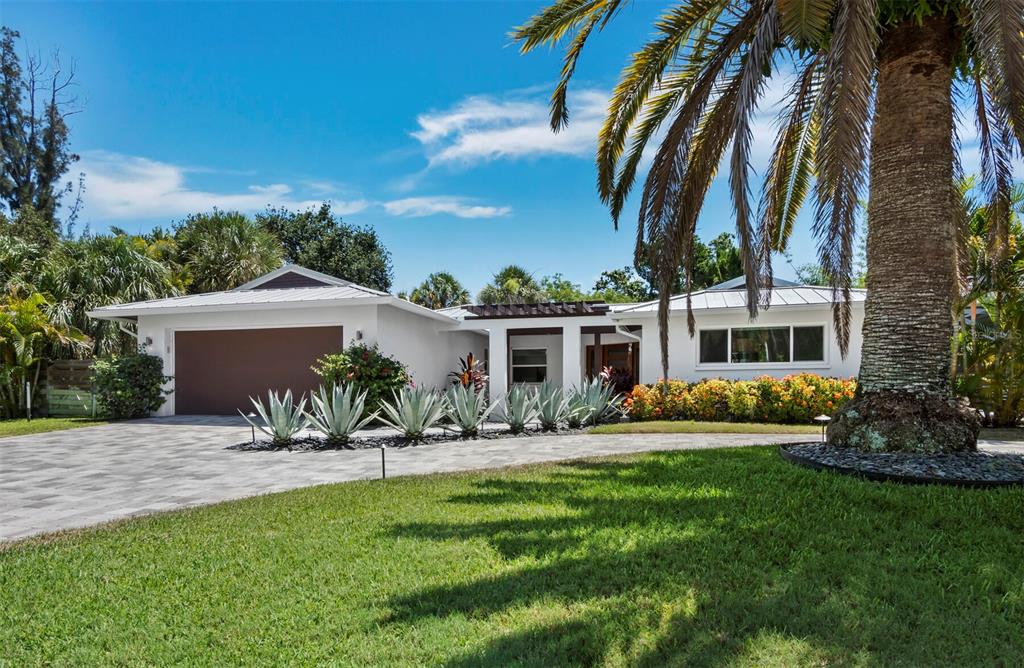 A single-story white house with a metal roof, a paved driveway, and palm trees — 622 TROPICAL CIRCLE, SARASOTA, FL