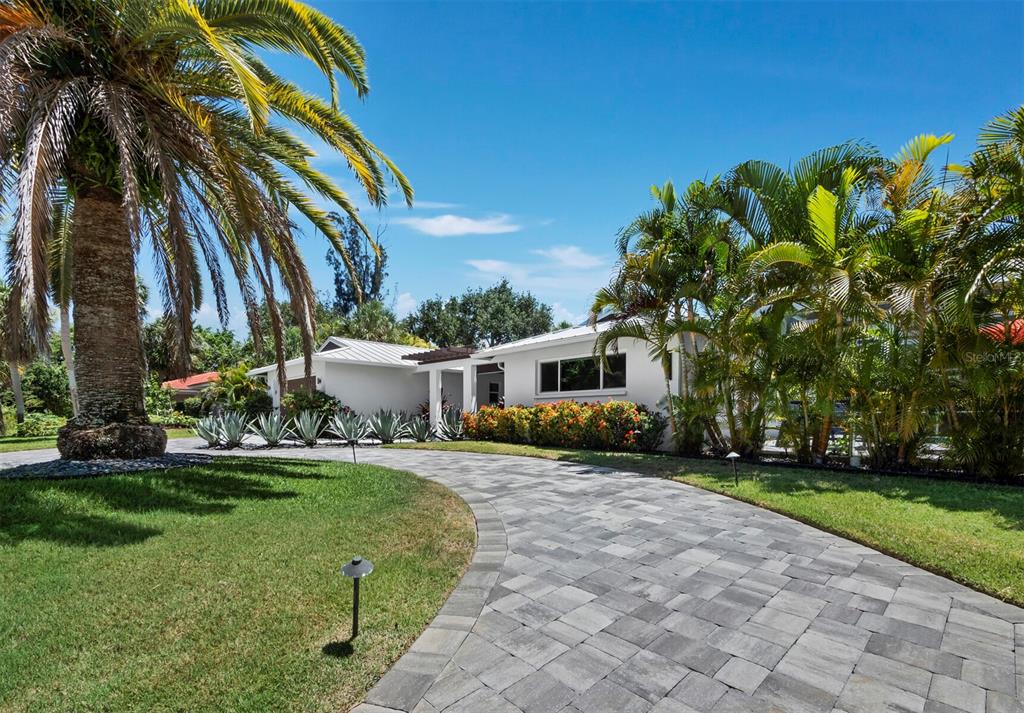A white house with a paved driveway and palm trees under a clear blue sky — 622 TROPICAL CIRCLE, SARASOTA, FL