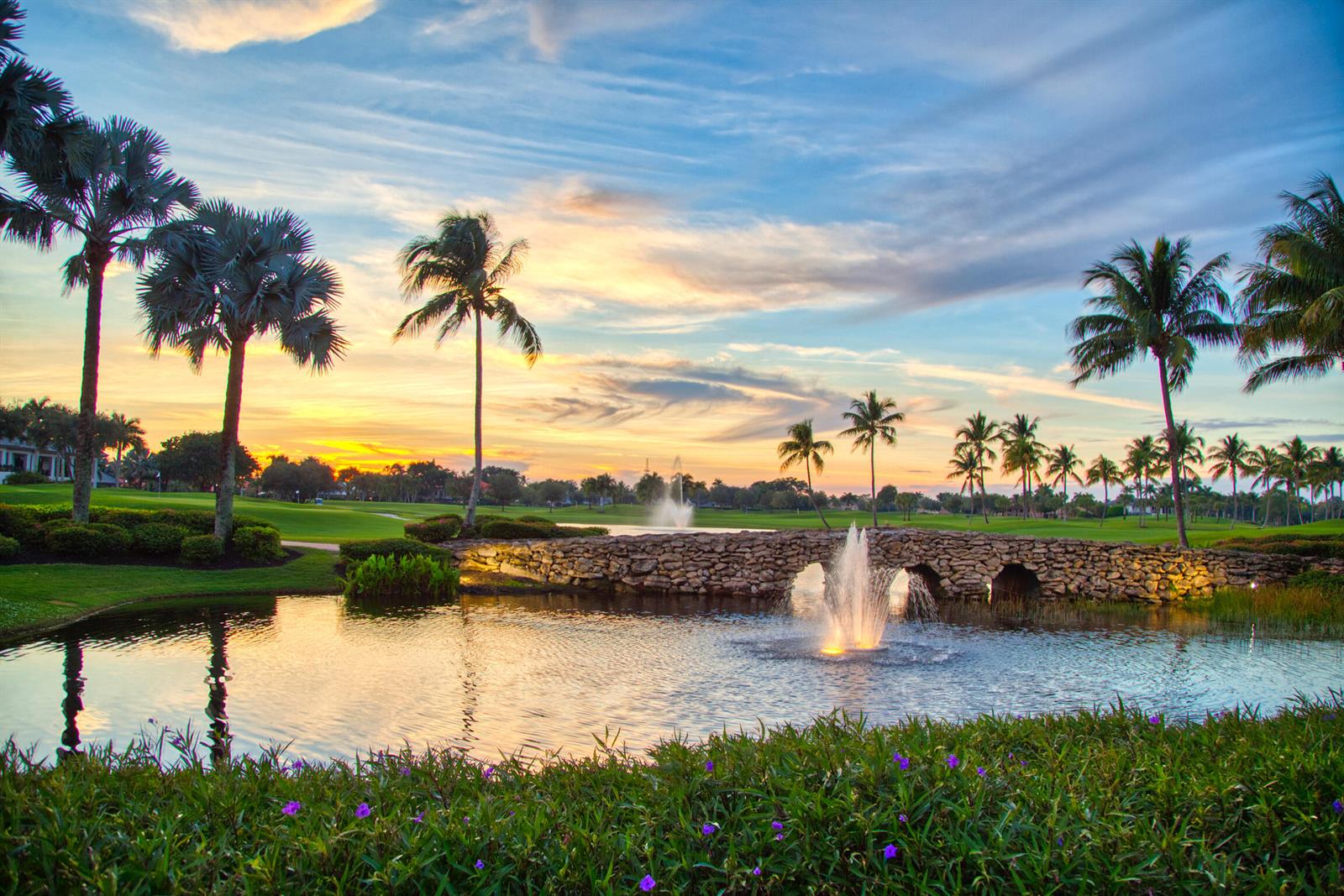 A stone bridge crosses a pond with a fountain on a golf course at sunset — 7370 Orangewood Lane # 303, Boca Raton FL 33433, BOCA RATON, FL