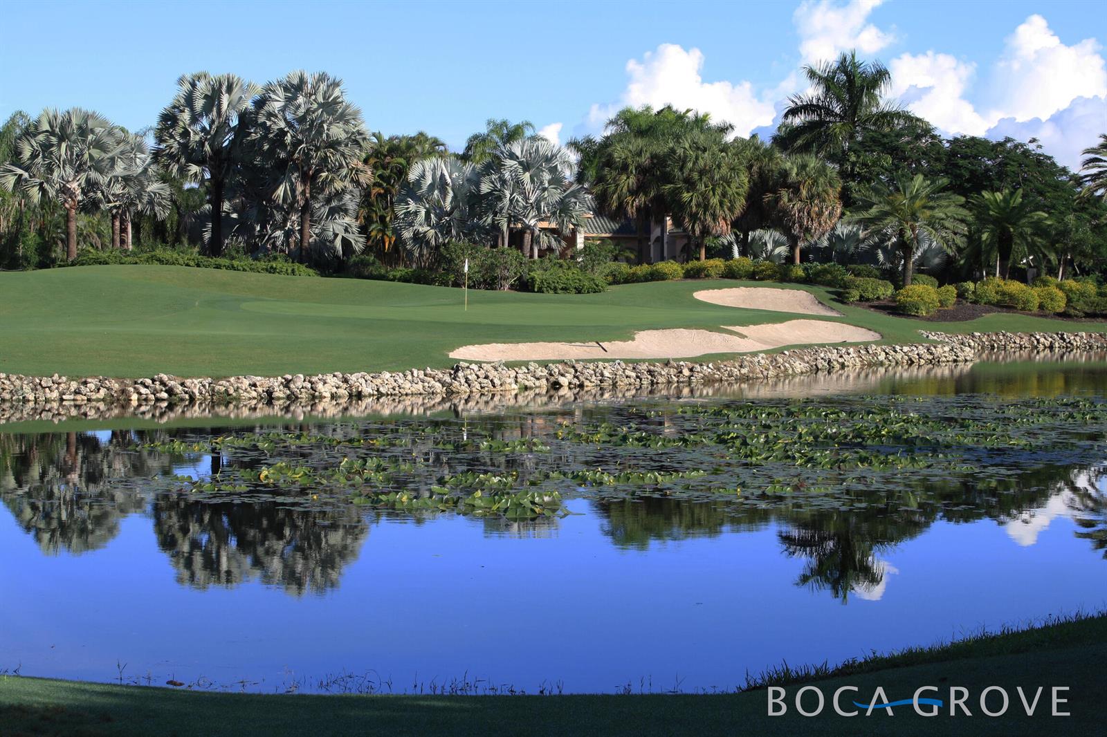 A golf course green sits behind a pond with lily pads and a rock border — 7370 Orangewood Lane # 303, Boca Raton FL 33433, BOCA RATON, FL