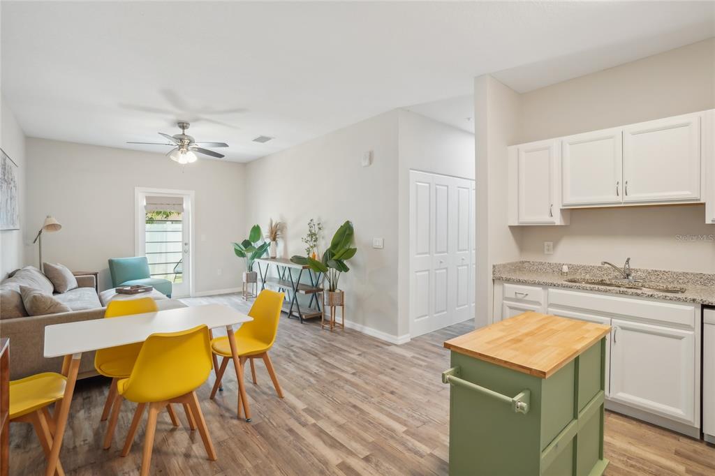 A living and dining area features a kitchen island, white cabinets, and yellow chairs — 14524 N NEBRASKA AVENUE UNIT 204A, TAMPA, FL