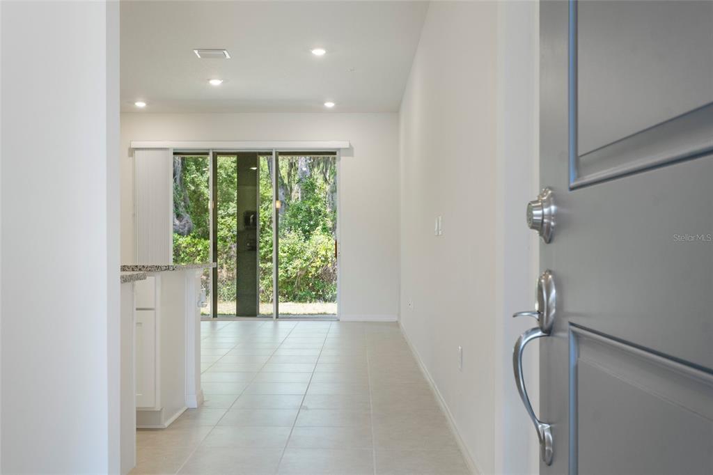 A view from a doorway into a tiled living area with sliding glass patio doors — 5273 LUISA COURT, ST CLOUD, FL