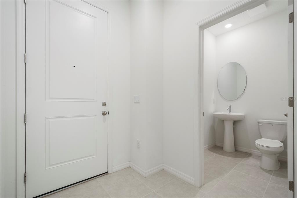 A white front door stands next to a small bathroom with a pedestal sink — 5273 LUISA COURT, ST CLOUD, FL