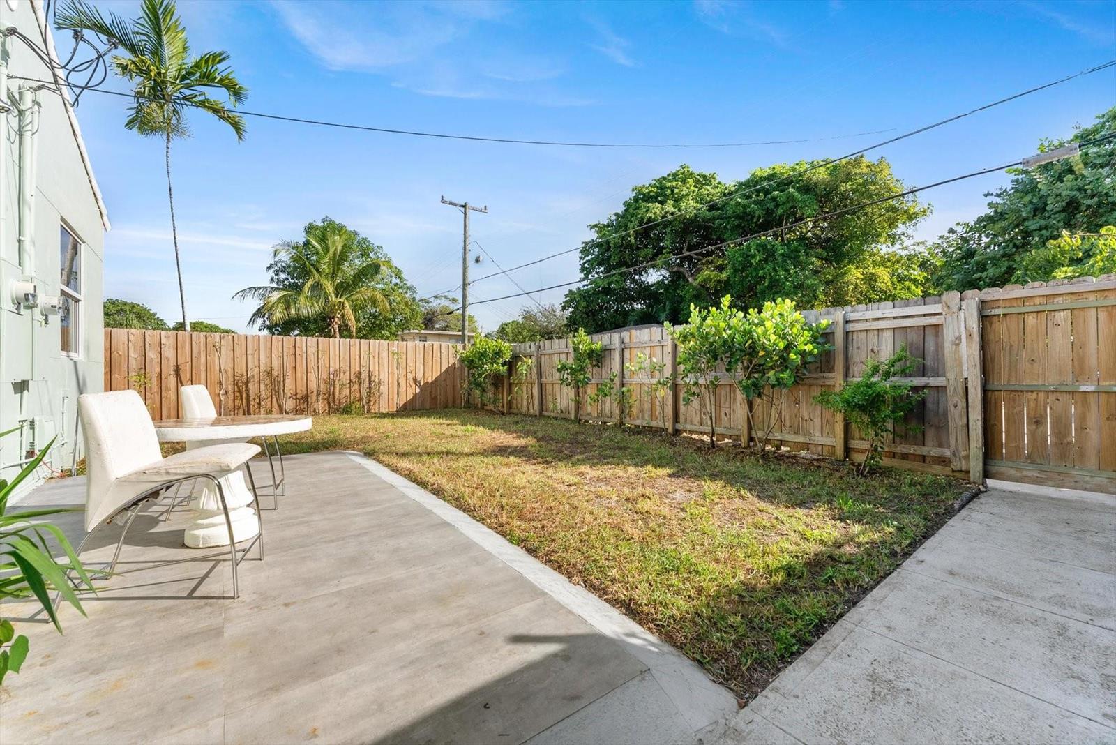 A backyard features a concrete patio, a small lawn, and a wooden privacy fence — 1928 Adams Street, Hollywood FL 33020, HOLLYWOOD, FL