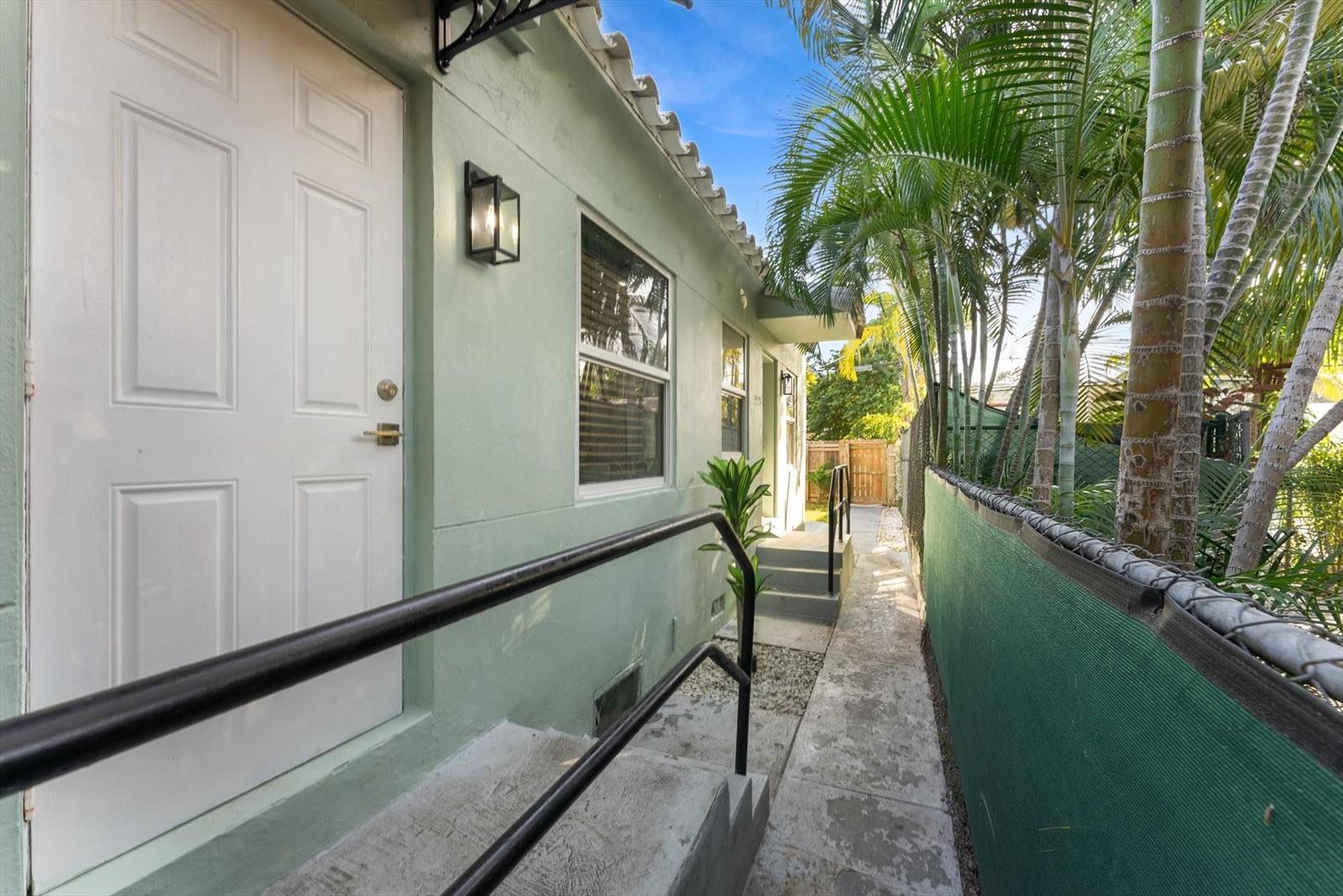 A narrow concrete walkway runs alongside a light green building with a white door — 1928 Adams Street, Hollywood FL 33020, HOLLYWOOD, FL