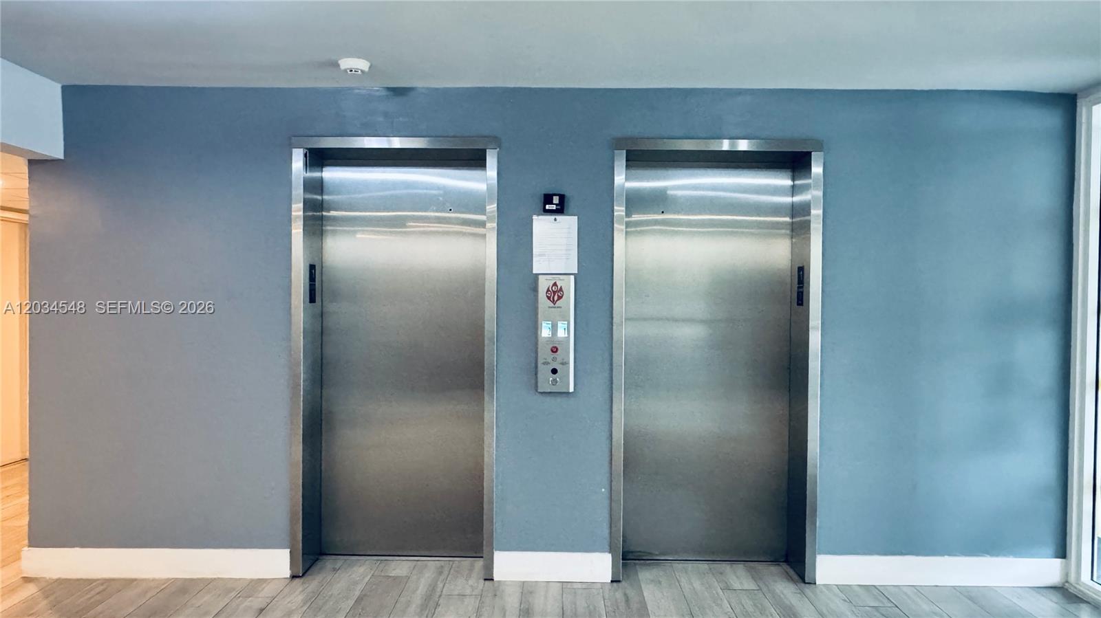 Two stainless steel elevator doors are set into a blue wall above wood-look flooring — 9125 SW 77th Ave # 501, Miami FL 33156, MIAMI, FL