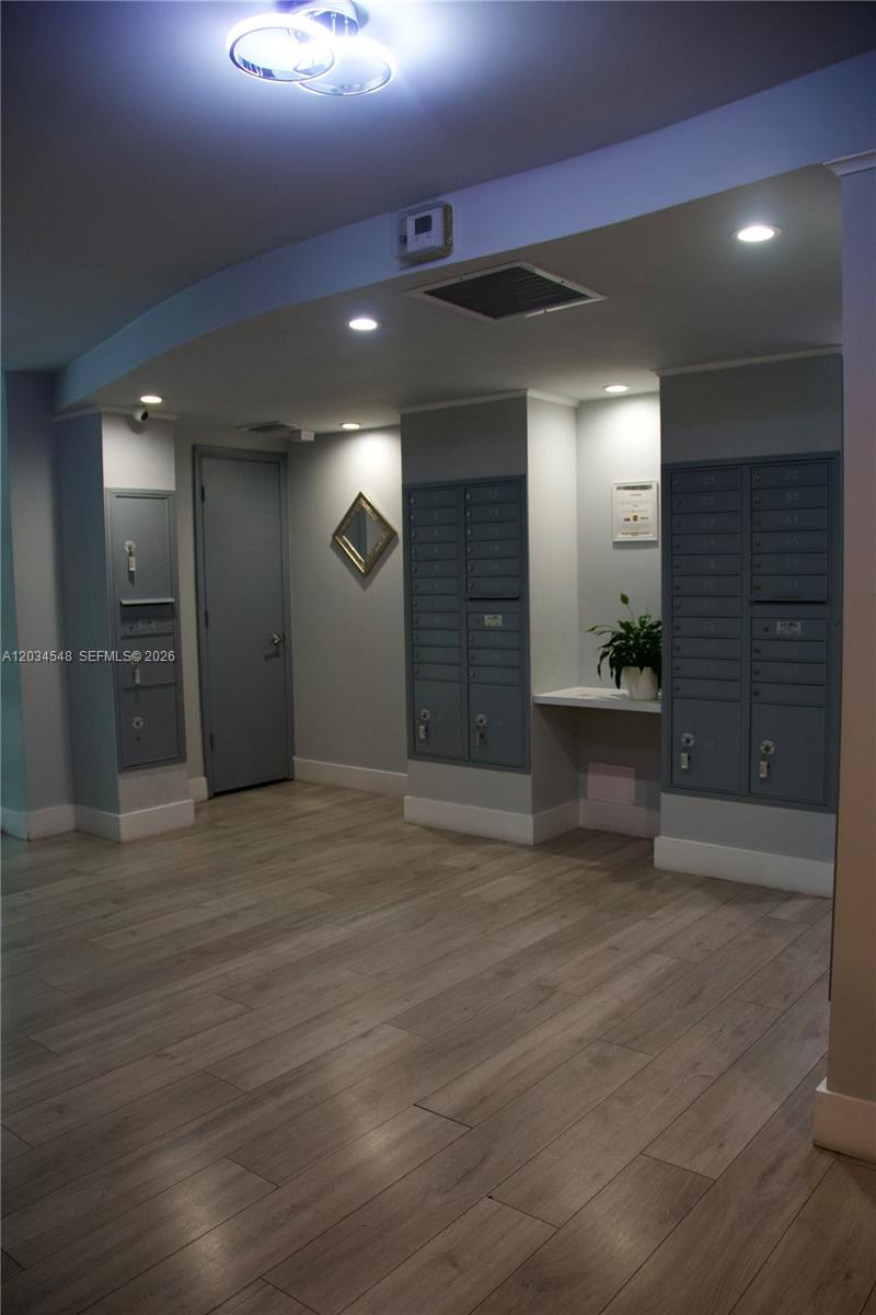 A mailroom features gray walls, wood-look flooring, recessed lighting, and multiple banks of mailboxes — 9125 SW 77th Ave # 501, Miami FL 33156, MIAMI, FL