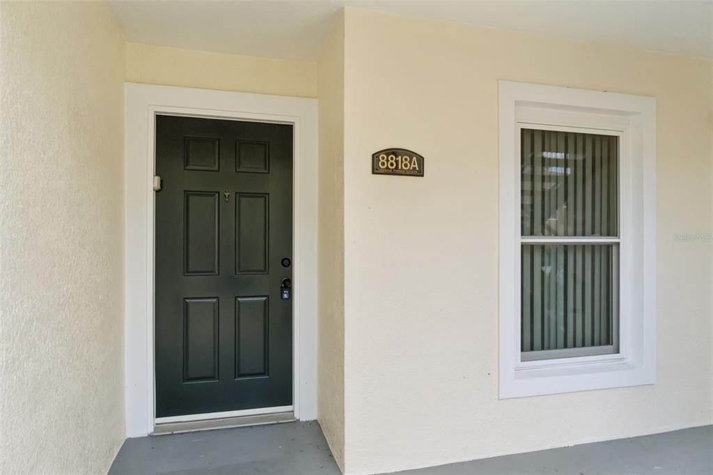 A dark green front door and a window with vertical blinds on a beige exterior — 8818 GRAND PALMS CIRCLE UNIT A, KISSIMMEE, FL