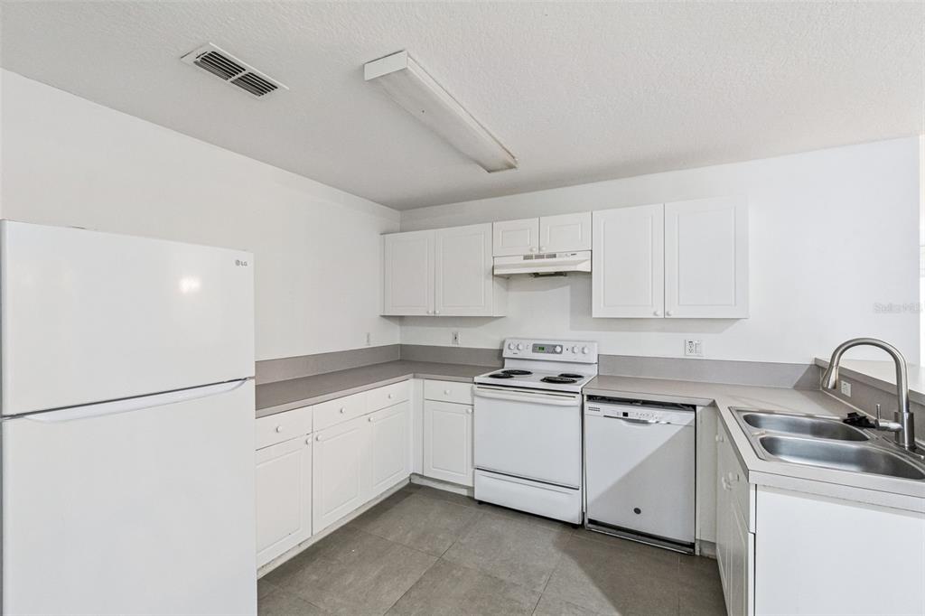 A kitchen with white cabinets, white appliances, gray countertops, and tile flooring — 8818 GRAND PALMS CIRCLE UNIT A, KISSIMMEE, FL