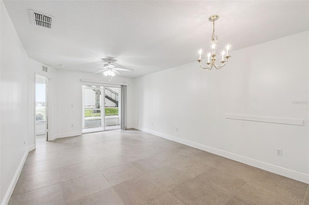 An empty room with white walls, tile flooring, a ceiling fan, and a chandelier — 8818 GRAND PALMS CIRCLE UNIT A, KISSIMMEE, FL