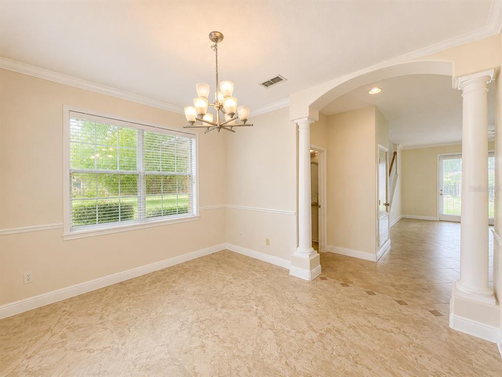 A dining room features tile flooring, a chandelier, white columns, and a large window — 1409 MICHIGAN AVENUE, WINTER PARK, FL