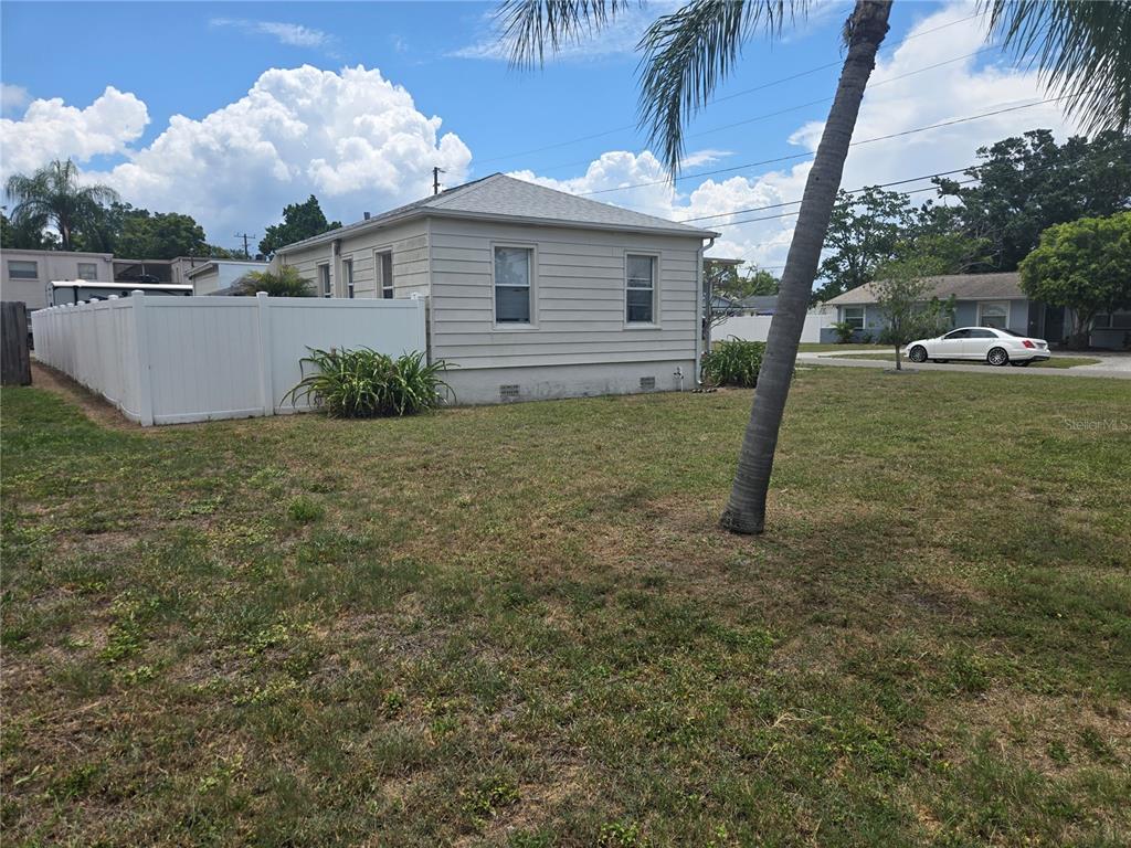 A side view of a light-colored house with horizontal siding and a white vinyl fence — 146 NE MADISON CIRCLE N, ST PETERSBURG, FL