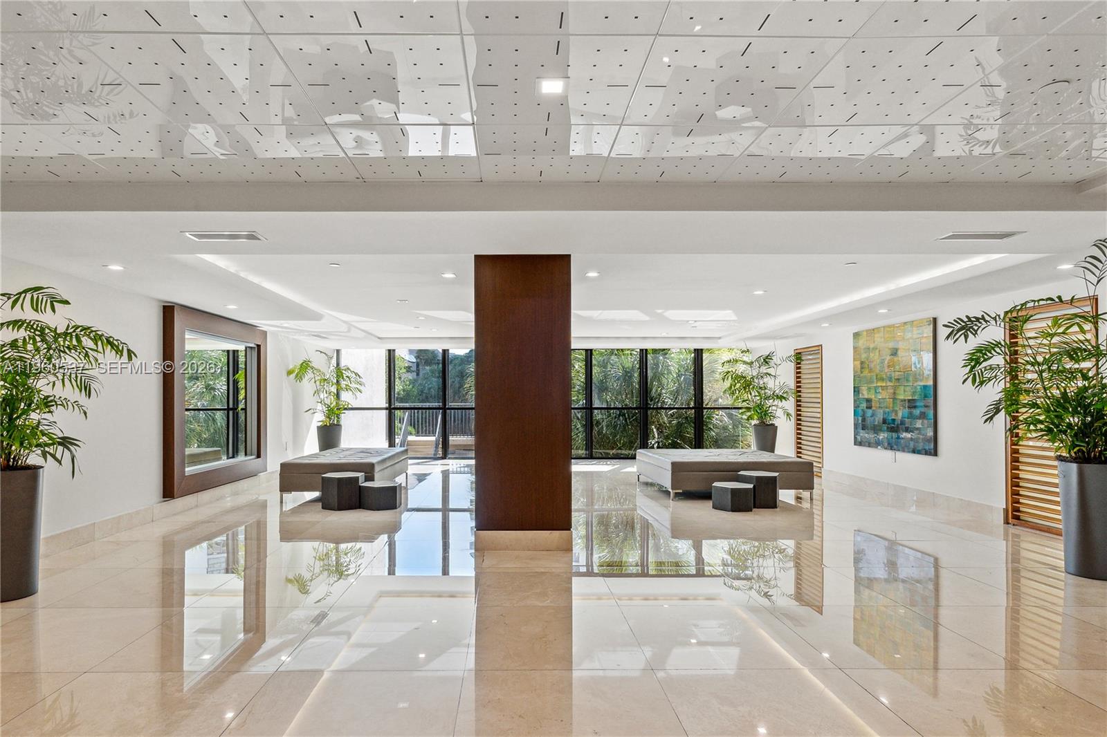 A modern lobby features polished tile floors, a central wooden pillar, and floor-to-ceiling windows — 540 Brickell Key Dr # 505, Miami FL 33131, MIAMI, FL