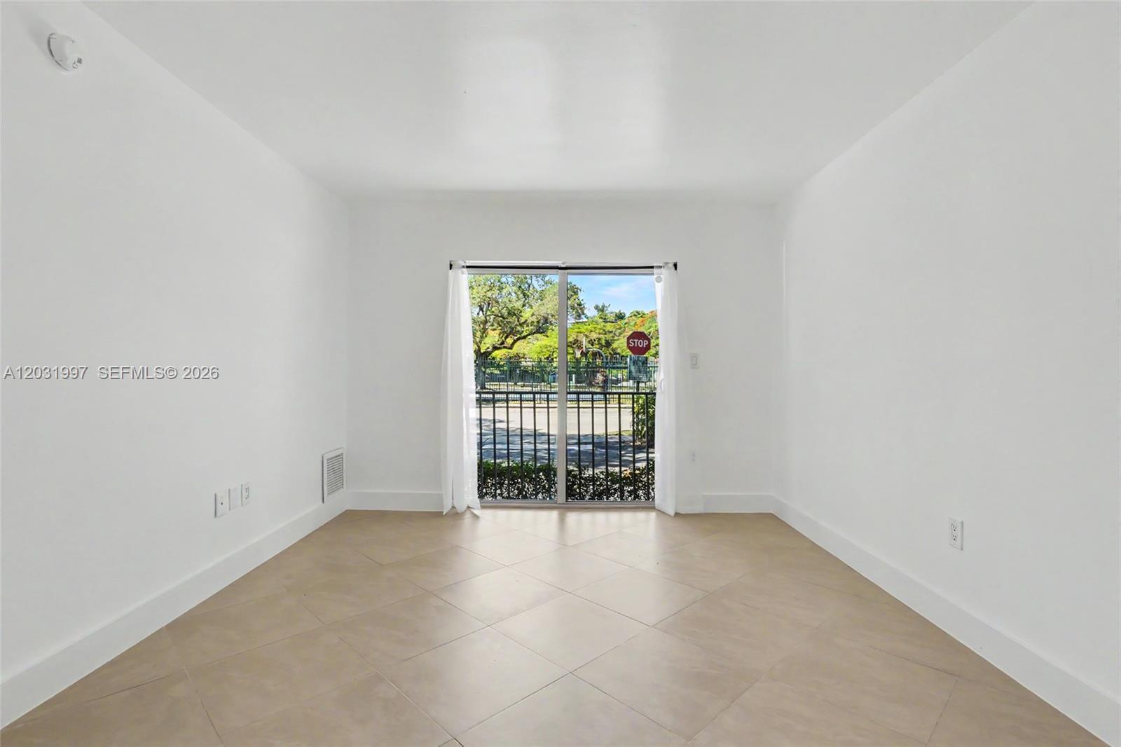 An empty room with white walls, tile flooring, and a sliding glass door — 445 SW 11th St # 102, Miami FL 33130, MIAMI, FL